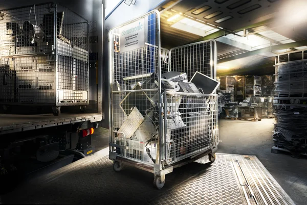 Rollwagen mit Elektroschrott in einem Lagerhaus, Licht dringt durch das Dach.