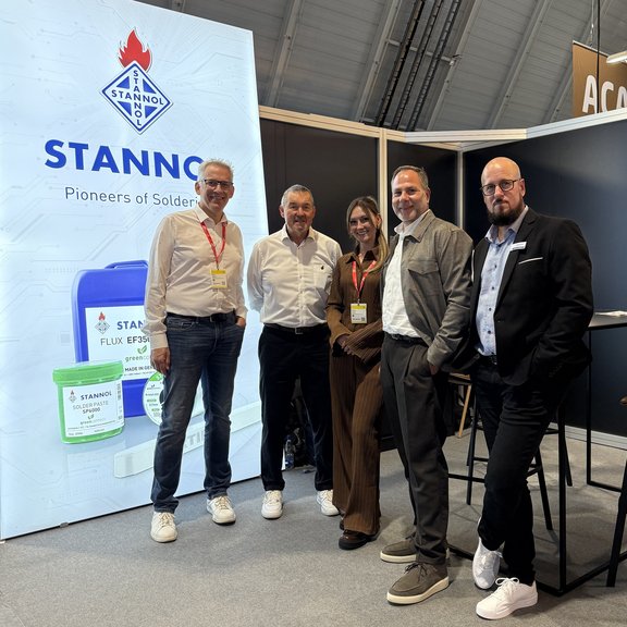 [Translate to Englisch:] Fünf Personen stehen vor einem Messestand mit Stannol-Logo.