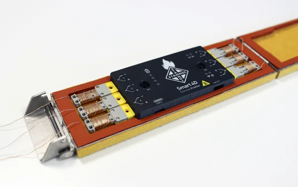 Electronic component with cable connections and black cover, lying on a table.