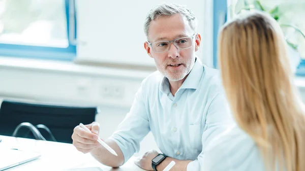Zwei Personen im Gespräch in einem Büro.