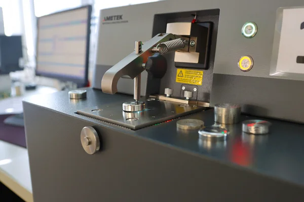 The picture shows a grey apparatus, a spark spectrometer, for analysing solder baths.
