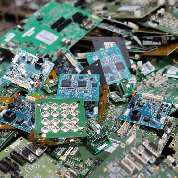 Haufen ausrangierter grüner Leiterplatten mit verschiedenen elektronischen Komponenten.