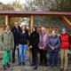 The picture shows a group of seven men and women in front of a roofed insect hotel.