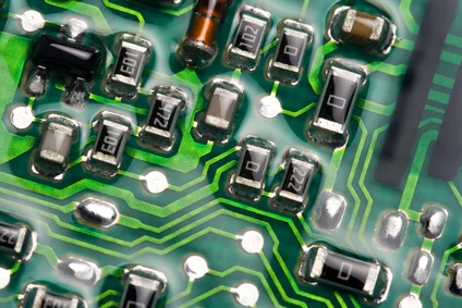Nahaufnahme einer grün-schwarzen Leiterplatte mit vielen elektronischen Bauteilen.