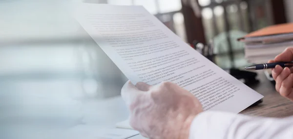 The picture shows a hand holding a written sheet of paper.