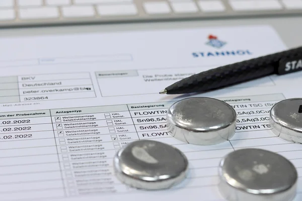 Dokument, Stift und runde Metallteile auf einem Schreibtisch.