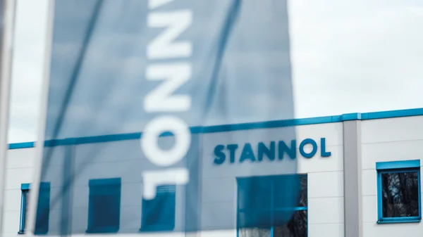 Gebäude mit blauer Fahne und Schriftzug "STANNOL" im Vordergrund.