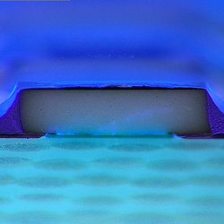 Unter UV-Licht sieht man die vollständige Schutzlackbeschichtung der scharfen kanten eines Bauteils.