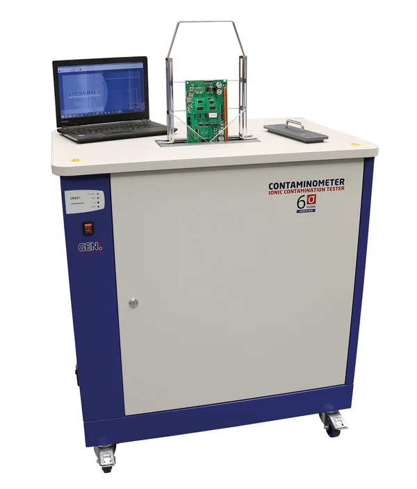 The picture shows a contaminometer from GEN3 Systems. A circuit board is mounted in a holder and is lowered into the device through an opening. To the left is a laptop.
