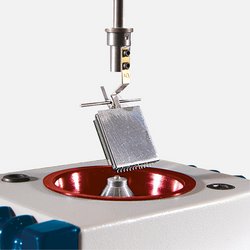 Auf dem Bild ist eine Benetungswaage zu sehen: In einem Halter ist ein Bauteil befestigt, das langsam auf eine kleine Lotkugel herabgelassen wird.