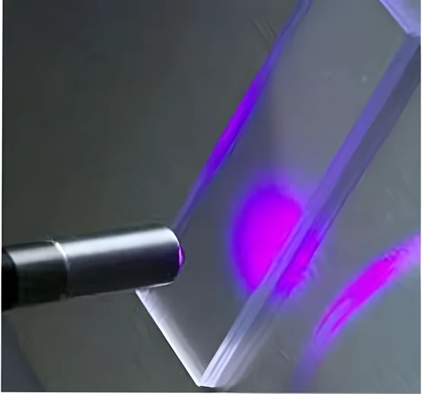 Lila Laserstrahl trifft auf transparentes Prisma.