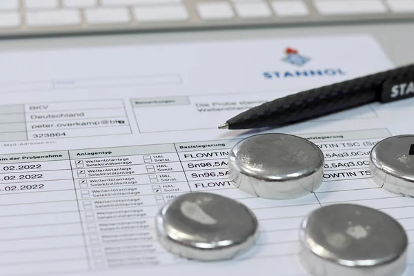 The picture shows an analysis form from Stannol, a biro and four solder samples in the form of pellets.