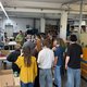 Personengruppe mit Kopfhörern in einem industriellen Raum, hört einen Vortrag.