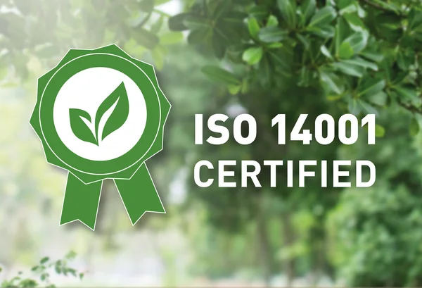 The picture shows a background with green leaves. In the foreground is a stylised green ribbon with two leaves, with the ISO14001 certified logo next to it.