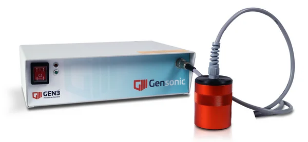 Auf dem Bild ist der Gensonic von Gen3 Systems zu sehen, ein hellgraues, rechteckiges Gerät, das per Kabel mit einem roten, zylindrischen Ultraschallgerät verbunden ist.