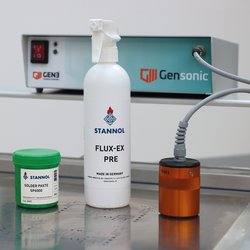 Auf dem Bild sind das Ultraschall-Reinigungsgerät Gensonic von Gen3 inklusive orangefarbenem Ultraschallschwingkopf, eine grüne Lotpastendose mit SP6000 Lotpaste von Stannol und eine weiße Sprühflasche Flux-Ex Pre-Reiniger von Stannol zu sehen.