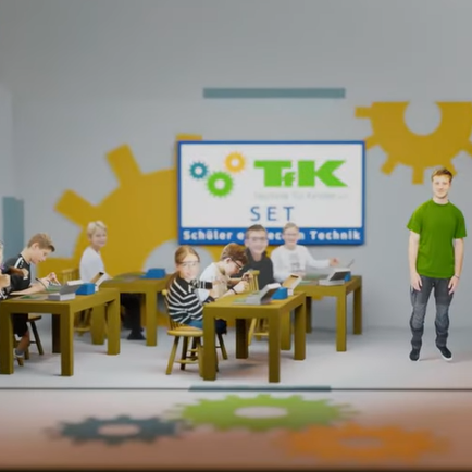Das Bild zeigt einen Ausschnitt aus dem Weihnachtsvideo des Vereins Technik für Kinder. Kinder sitzen an verschiedenen Tischen und beschäftigen sich verschiedenen Aufgaben , zum Beipisel Löten Im Hintergrund ist eine Tafel mit dem Logo des TFK zu sehen.