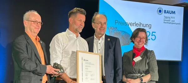 Four people on a stage holding an award an a certificate.