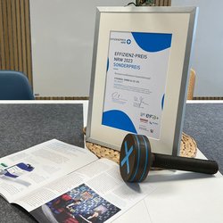 Auf dem Bild ist der Award, die Urkunde und ein Artikel in einem Magazin zu sehen.