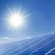 The picture shows a PV system, a blue sky and a bright sun.