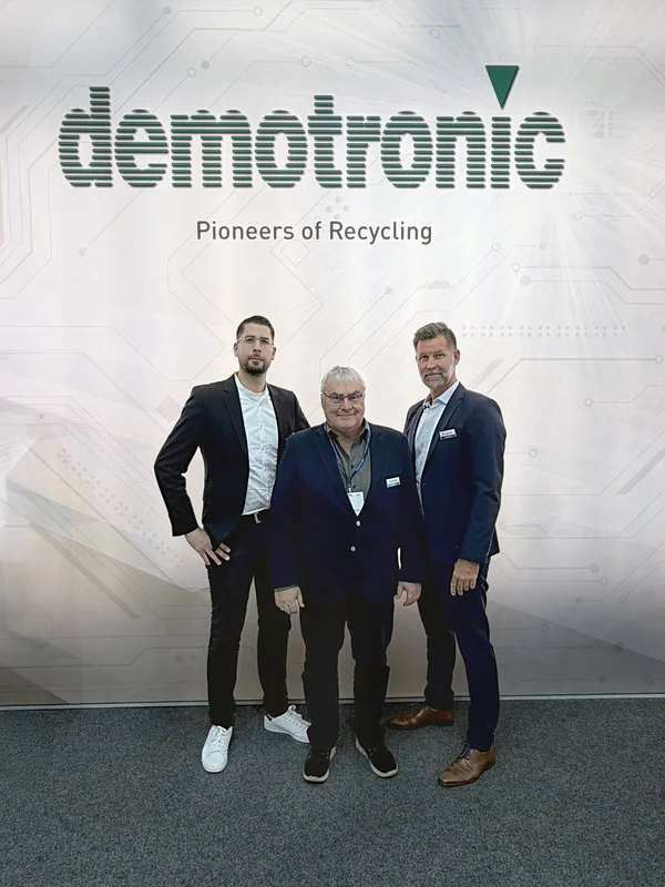 Drei Männer vor einem "demotronic"-Banner.