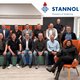 Gruppe von Personen in einem Raum, lächelnd, vor dem Stannol-Logo und Pflanzen.