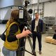 Auf dem Bild ist eine Kamerfrau zu sehen, die Geschäftsführer Marco Dörr für einen Fernsehbeitrag aufnimmt. Sie stehen in der Produktionshalle von Stannol.