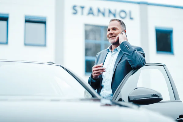 Mann telefoniert bevor er in das Auto einsteigt